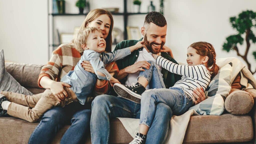 Happy family of four smiling and enjoying their time together in the living room