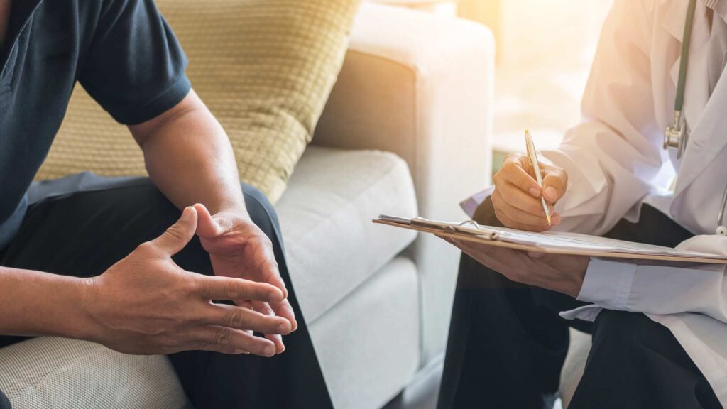 Male patient sitting with male doctor reviewing his options for medication assisted treatment in Massachusetts.